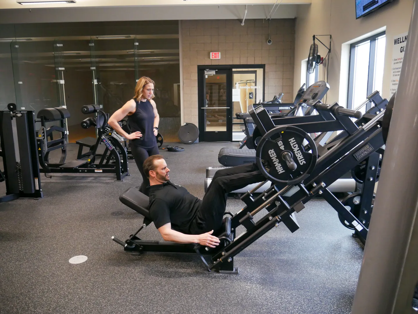 YMCA personal trainer showing a woman how to use leg press machine