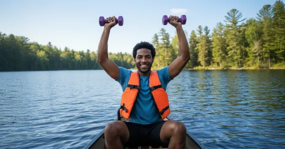 man in a canoe holding dumbbells above his head