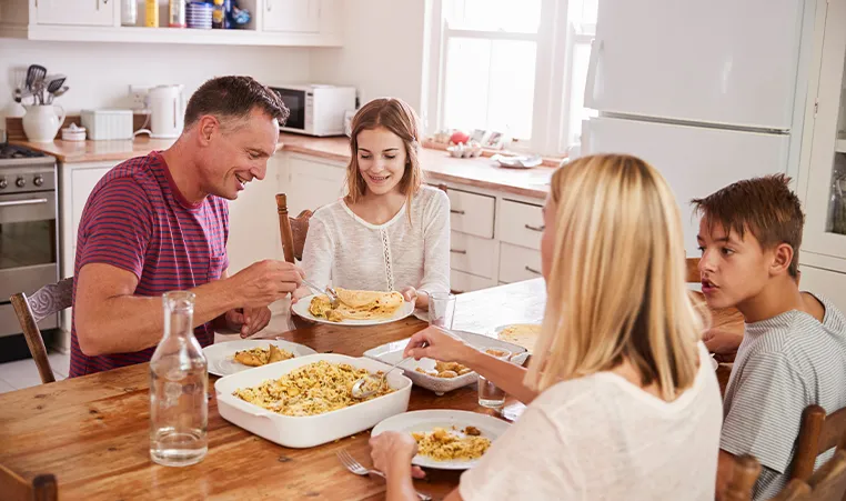 parents and children eating dinner around kitchen table