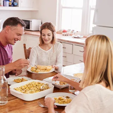 parents and children eating dinner around kitchen table