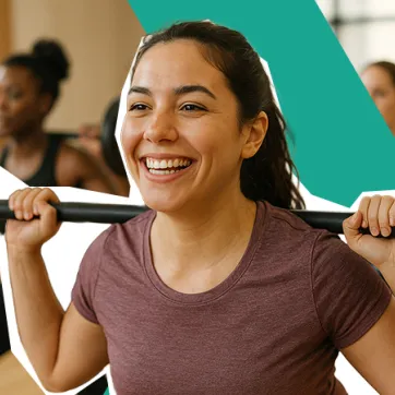 smiling woman lifting a barbell in a group class